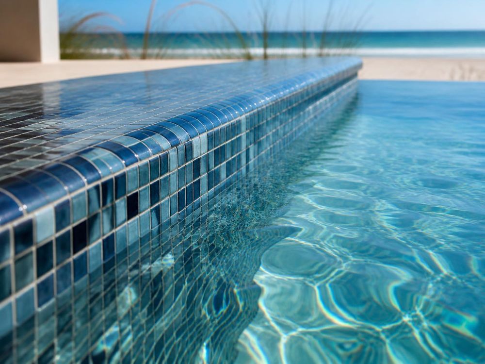 Glass tile waterline of a coastal Florida pool with the beach beyond